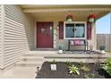 Inviting front porch with seating, charming decor, and pleasant curb appeal with colorful plants and flowers at 4605 Clairmont Dr, Columbus, IN 47203