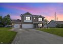 Two-story brick house with attached garage and manicured lawn at dusk at 5030 E 800 N, Columbus, IN 47203