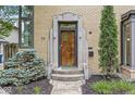 Close-up shot of the front door showcasing its unique design and stone frame with manicured shrubbery at 518 Buckingham Dr, Indianapolis, IN 46208