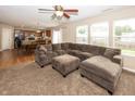 Spacious living room with a plush sectional sofa, a ceiling fan, and large windows that offer plenty of natural light at 5215 Climbing Rose Pl, Indianapolis, IN 46254
