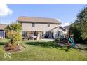 Spacious backyard with a large lawn, patio seating area, and a playset for outdoor enjoyment at 7249 Red Maple Dr, Zionsville, IN 46077