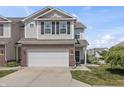 Well-kept townhome with a two-car garage and landscaping against a blue sky at 9709 Prairie Smoke Dr, Noblesville, IN 46060