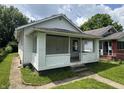 Cozy home featuring a covered front porch and mature trees in the surrounding yard at 1445 W 34Th St, Indianapolis, IN 46208