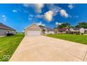 Spacious front yard with a long driveway leading to an attached garage and well-maintained lawn at 32 Downing Dr, Trafalgar, IN 46181