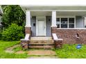 Inviting front porch with brick columns, gray siding, and a secure ADT security system at 3652 N Kenwood Ave, Indianapolis, IN 46208
