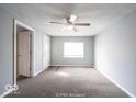 Bright living room with carpet flooring, a ceiling fan, and a large window for natural light at 5050 W Regent St, Indianapolis, IN 46241