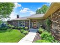 Inviting brick home features a red front door and charming landscaped front porch at 5215 Limestone Ct, Indianapolis, IN 46237
