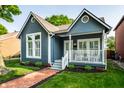 Lovely blue home with a cozy front porch, lush green lawn, and a welcoming brick pathway at 608 E 9Th St, Indianapolis, IN 46202