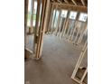 Unfinished bedroom showing wall studs, plywood flooring, and three windows bringing in natural light at 637 Firefly Ct, Greenfield, IN 46140