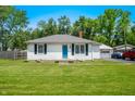 Inviting ranch home with a bright blue front door, surrounded by lush greenery and a well kept lawn at 120 Hoss Rd, Indianapolis, IN 46217