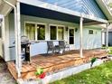 Close up of the home's covered porch including outdoor chairs and grill on a wooden deck at 1437 E Pleasant Run Pkwy S Dr, Indianapolis, IN 46203