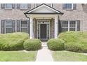 A welcoming front porch with a black door, framed by white pillars and manicured greenery at 15201 Slateford Rd, Noblesville, IN 46062