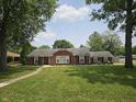 Traditional brick home featuring large front yard with mature trees and simple landscaping at 1628 Edgewood Dr, Anderson, IN 46011
