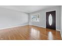Bright living room featuring hardwood floors, a large window, fresh paint, and a stylish front door at 2908 N Routiers Ave, Indianapolis, IN 46219