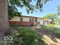 Brick and vinyl home featuring mature tree and green lawn at 3106 Southwest Dr, Indianapolis, IN 46241