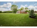Expansive backyard featuring a lush lawn, mature trees, and a covered porch at 4901 E County Road 100 N, Avon, IN 46123