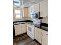 Traditional-style kitchen with white appliances, dark countertops and wood-look flooring at 6322 Commons Dr, Indianapolis, IN 46254
