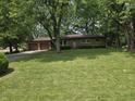 Traditional brick home featuring an attached two-car garage and a well-manicured lawn with mature trees at 7088 Sandalwood Dr, Indianapolis, IN 46217