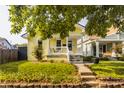 Inviting yellow house featuring a cozy front porch, well-kept lawn, and beautiful landscaping at 743 Sanders St, Indianapolis, IN 46203