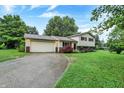 Well-kept two-story home with an attached garage and a long driveway, complemented by mature trees at 7504 Troon Ct, Indianapolis, IN 46237