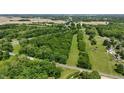 Aerial view overlooking wooded property, road, and surrounding fields offering a serene environment at 7811 N County Road 500 E, Pittsboro, IN 46167