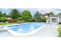 Large pool with diving board, concrete pool surround, and mature landscaping offers a resort-like experience at 164 Wellington Pkwy, Noblesville, IN 46060