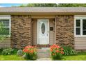 Close-up of the front entrance with a decorative white door and blooming flowers at 3210 Flintwood Dr, Columbus, IN 47203