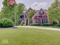 Beautiful two-story brick home featuring a lush green lawn and mature trees at 4075 Dartmoor Dr, Greenwood, IN 46143