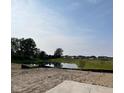 Scenic view of a calm pond reflecting the sky, surrounded by lush trees and a neighborhood in the background at 5002 Amber Wood Dr, Lawrence, IN 46235