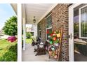 Inviting covered porch with brick siding, wood benches, colorful flower planters, and a ceiling fan at 7733 Chestnut Eagle Ct, Zionsville, IN 46077
