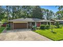 Charming home with manicured lawn, brick facade, dark roof, and a paved driveway leading to an attached garage at 8635 Bishops Ln, Indianapolis, IN 46217