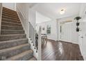 Bright foyer with hardwood floors, staircase, and view into the adjacent dining area at 9840 N Anchor Bnd, McCordsville, IN 46055