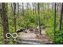 Secluded backyard fire pit area with gravel, surrounded by mature trees and natural forest setting at 10707 Club Chase, Fishers, IN 46037