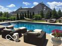 A backyard oasis featuring a large pool with comfortable lounge seating and well manicured landscaping at 10707 Club Chase, Fishers, IN 46037