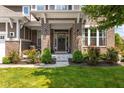 Inviting front porch with brick pillars and vibrant flowerbeds, creating a warm and welcoming entrance at 15047 Glenmoor Cir, Carmel, IN 46033
