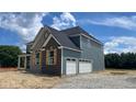 Side exterior of a new construction home highlighting the attached two-car garage and complementary stone and siding finishes at 1919 Delp Ct, Avon, IN 46123