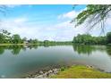 Picturesque lake view with visible rocky edge and lush greenery on a beautiful day at 3695 Windsor Pl, Martinsville, IN 46151