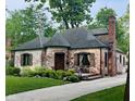 Beautiful brick home showcasing lush landscaping, a unique turret, and a welcoming pathway at 5677 Carrollton Ave, Indianapolis, IN 46220