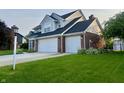 Charming home with brick facade, two-car garage, green lawn, and a small decorative lamp post at the end of the driveway at 7532 Perilla Ct, Indianapolis, IN 46237
