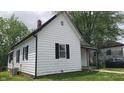 An exterior side view of a well-lit home featuring white siding and black shutters at 7879 Main St, Coatesville, IN 46121