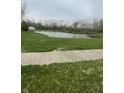 A serene pond bordered by lush green grass and mature trees, offering a peaceful view at 8457 Kousa Dr, Indianapolis, IN 46234
