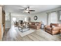 Spacious living room featuring leather furniture, a ceiling fan, and light wood flooring at 10197 Apple Blossom Cir, Fishers, IN 46038