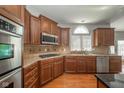 Well-lit kitchen with wood cabinets, granite countertops, stainless steel appliances, and hardwood floors at 10555 Serra Vista Pt, Fishers, IN 46040