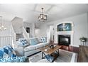 Cozy living room featuring a fireplace, gray sofa with patterned pillows, and dark hardwood floors at 11509 Reagan Dr, Fishers, IN 46038