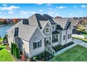 Aerial view of a beautiful two-story home with a three car garage on a well-manicured lawn near a lake at 13613 Lake Ridge Ln, McCordsville, IN 46055
