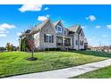 A well-manicured lawn and landscaping surround this beautiful two-story home with a stone and siding exterior at 13613 Lake Ridge Ln, McCordsville, IN 46055