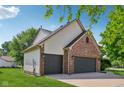 Side view of a three-car garage with brick and siding exterior and a well-maintained lawn at 13938 Charleswood Ct, Fishers, IN 46038