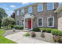 Charming two-story brick home with a vibrant red front door, white trim, and manicured landscaping at 16802 Oak Manor Dr, Westfield, IN 46074