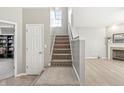 Carpeted stairs with a white banister leading to the upper level, next to a door and a view of the living room at 1829 Archbury Dr, Avon, IN 46123