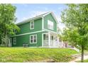 Inviting two-story home showcasing green siding, a covered front porch, and a well-manicured lawn at 2427 N Rural St, Indianapolis, IN 46218